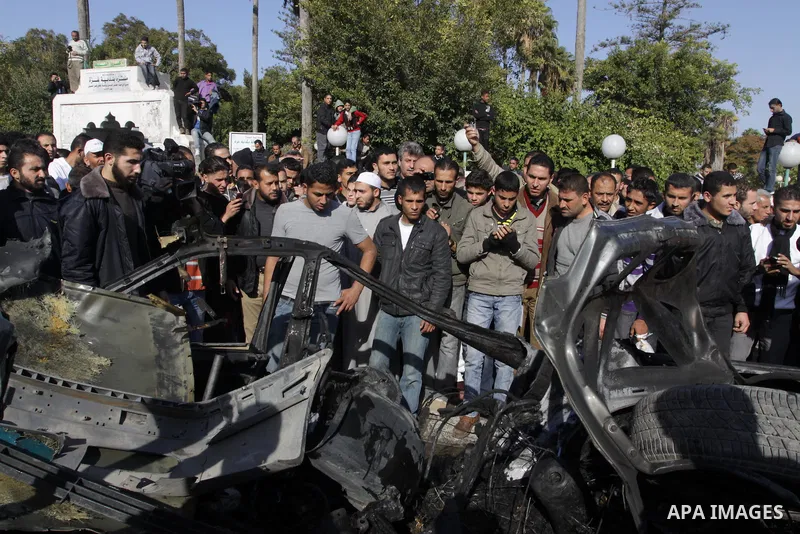 Palestinians crowd around the remains of a car hit by an Israeli air strike in Gaza City December 8, 2011. An Israeli air strike on the car killed at least two Hamas militants and wounded two others on a crowded Gaza str...