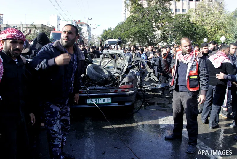 Palestinians crowd around the remains of a car hit by an Israeli air strike in Gaza City December 8, 2011. An Israeli air strike on the car killed at least two Hamas militants and wounded two others on a crowded Gaza str...