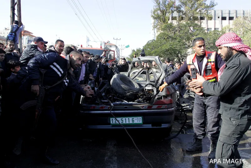 Palestinians crowd around the remains of a car hit by an Israeli air strike in Gaza City December 8, 2011. An Israeli air strike on the car killed at least two Hamas militants and wounded two others on a crowded Gaza str...