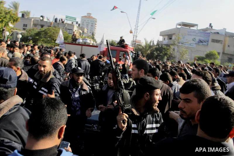 Palestinians crowd around the remains of a car hit by an Israeli air strike in Gaza City December 8, 2011. An Israeli air strike on the car killed at least two Hamas militants and wounded two others on a crowded Gaza str...