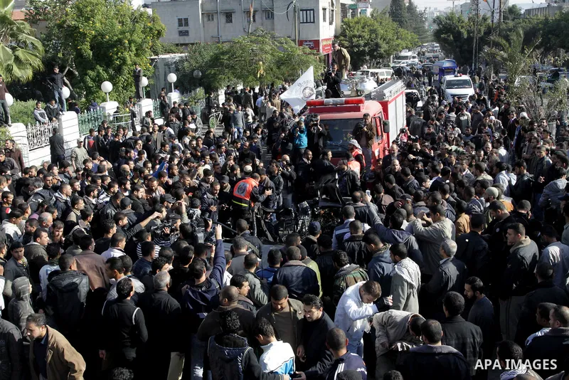 Palestinians crowd around the remains of a car hit by an Israeli air strike in Gaza City December 8, 2011. An Israeli air strike on the car killed at least two Hamas militants and wounded two others on a crowded Gaza str...