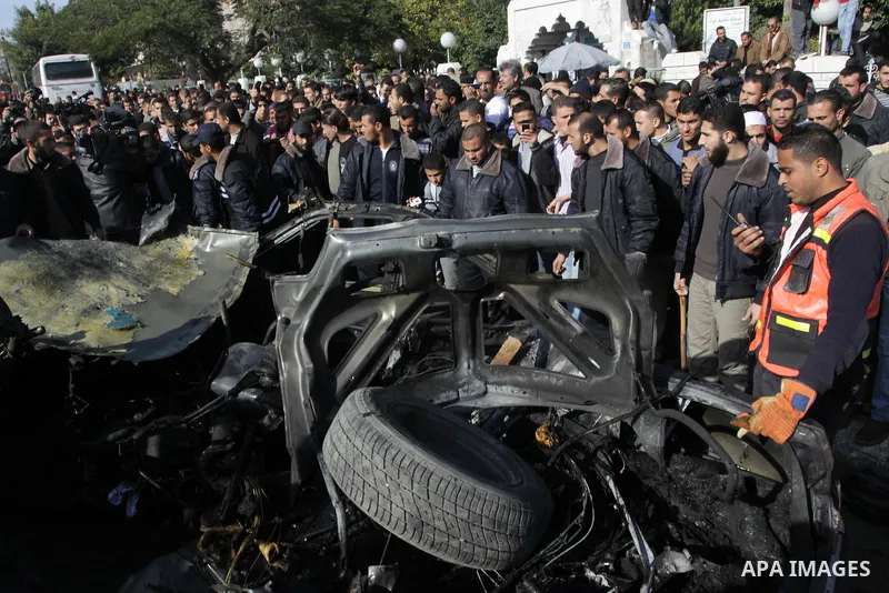 Palestinians crowd around the remains of a car hit by an Israeli air strike in Gaza City December 8, 2011. An Israeli air strike on the car killed at least two Hamas militants and wounded two others on a crowded Gaza str...