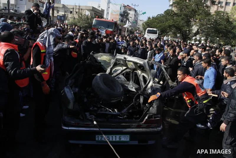 Palestinians crowd around the remains of a car hit by an Israeli air strike in Gaza City December 8, 2011. An Israeli air strike on the car killed at least two Hamas militants and wounded two others on a crowded Gaza str...