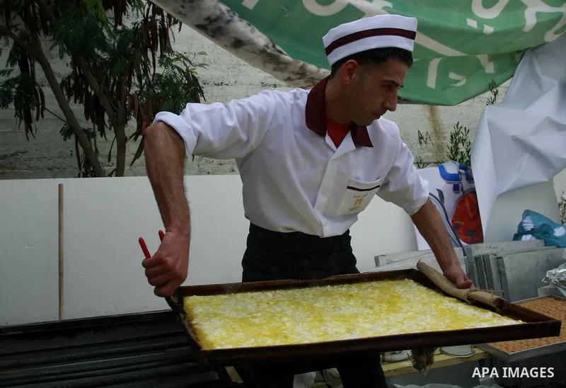 Palestinian bakers prepare a giant Kunafa, a favorite local sweet, during a celebration in the West Bank city of Nablus, Thursday, Dec. 8, 2011. Photo by Wagdi Eshtayah.
