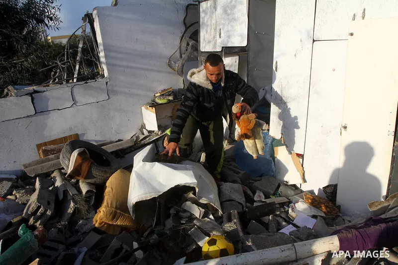 A Palestinian man holds toys as he looks at a house damaged in an Israeli air strike in Gaza City, on December 9, 2011. Violence across the Israeli-Gaza border escalated on Friday with Israeli air strikes killing at leas...