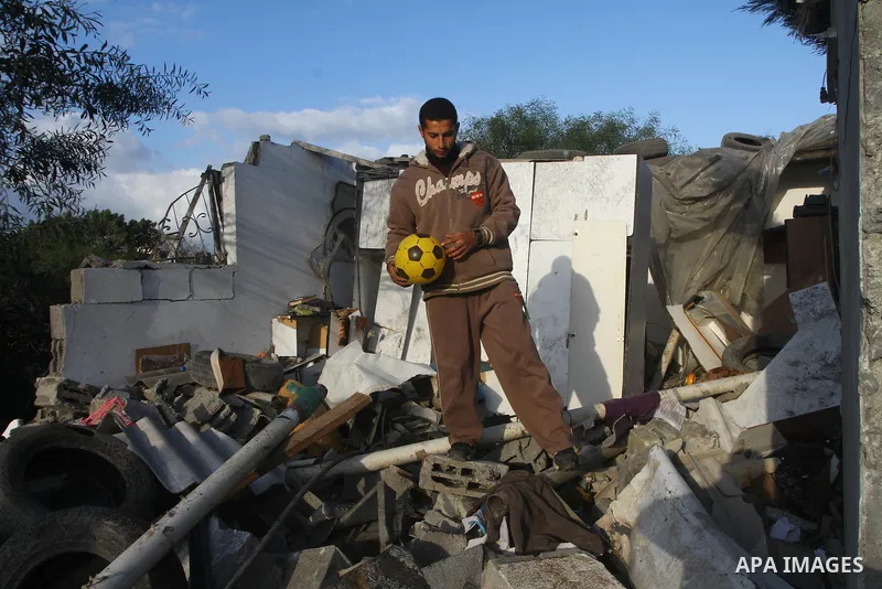 A Palestinian man holds toys as he looks at a house damaged in an Israeli air strike in Gaza City, on December 9, 2011. Violence across the Israeli-Gaza border escalated on Friday with Israeli air strikes killing at leas...