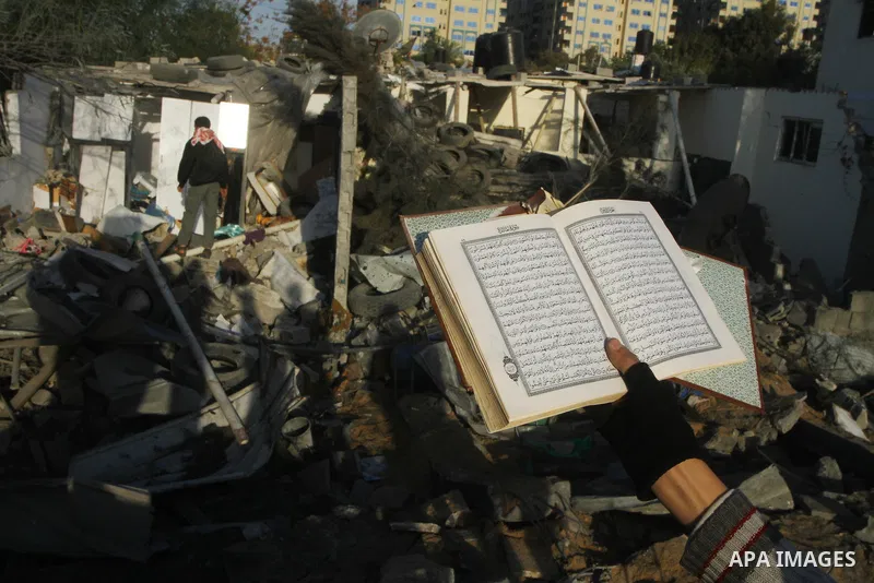 A Palestinian man hold the Qouran as he looks at a house damaged in an Israeli air strike in Gaza City December 9, 2011. Violence across the Israeli-Gaza border escalated on Friday with Israeli air strikes killing at lea...