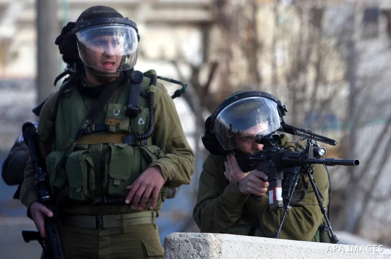 Israeli soldiers fire tear gas at Palestinian demonstrators during a protest against the construction of Israel's separation barrier in the West Bank village of Qalandia, near Ramallah, on December 9, 2011. Photo by Issa...