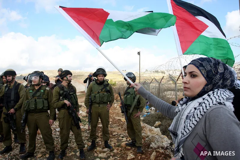 Palestinian demonstrators wave their national flag during a protest against the construction of Israel's separation barrier in the West Bank village of Qalandia, near Ramallah, on December 9, 2011. Photo by Issam Rimawi