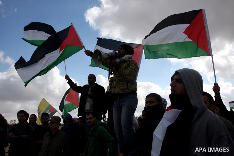 Palestinian demonstrators wave their national flag during a protest against the construction of Israel's separation barrier in the West Bank village of Qalandia, near Ramallah, on December 9, 2011. Photo by Issam Rimawi