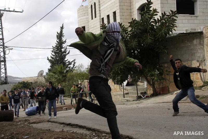Palestinian protesters throw stones towards Israeli soldiers during clashes that broke out at a weekly demonstration against Israeli-occupation in the northern West Bank village of Kfar Kadum on December 9, 2011. A Pales...