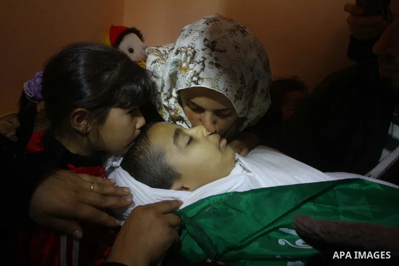 The mother (R) and sister of Palestinian boy Ramadan al-Zaalan, 12, mourn over his body during his funeral in Gaza City on December 10, 2011. Zaalan was killed with his father Bahjat in an Israeli air strike on a civilia...