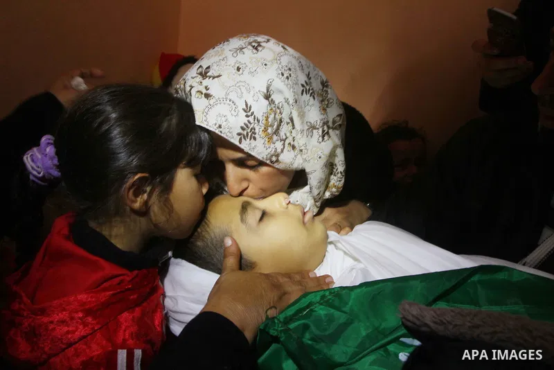 The mother (R) and sister of Palestinian boy Ramadan al-Zaalan, 12, mourn over his body during his funeral in Gaza City on December 10, 2011. Zaalan was killed with his father Bahjat in an Israeli air strike on a civilia...