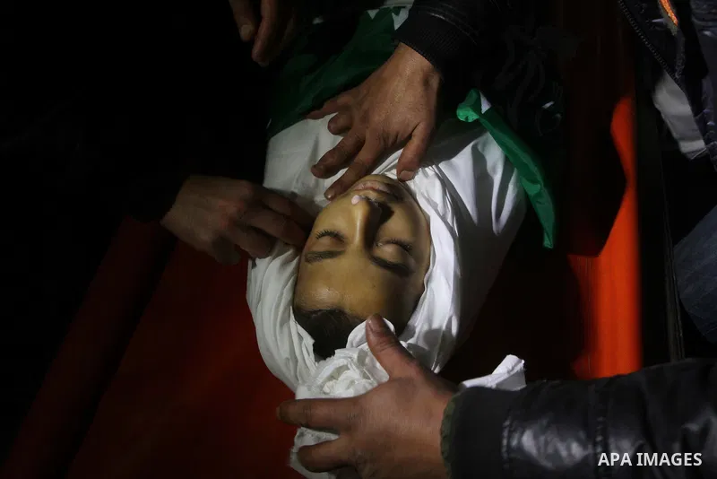 The body of Palestinian boy Ramadan al-Zaalan, 12, lies near mourners during his funeral in Gaza City on December 10, 2011. Zaalan was killed with his father Bahjat in an Israeli air strike on a civilian house in Gaza, m...