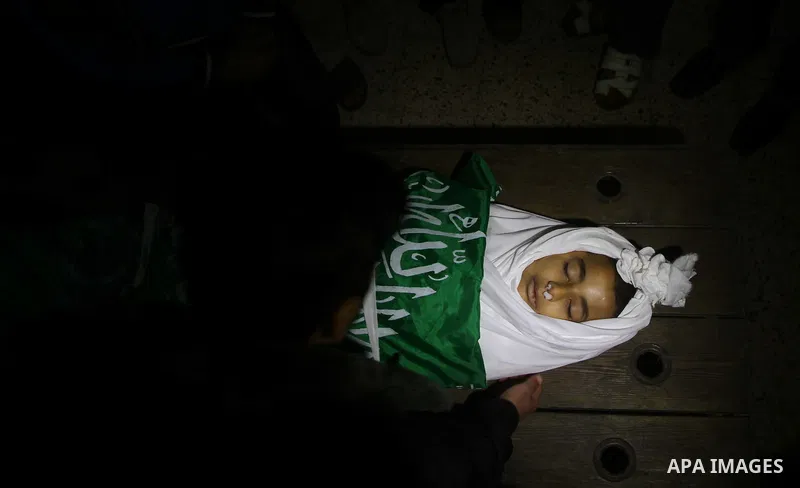 The body of Palestinian boy Ramadan al-Zaalan, 12, lies near mourners during his funeral in Gaza City on December 10, 2011. Zaalan was killed with his father Bahjat in an Israeli air strike on a civilian house in Gaza, m...