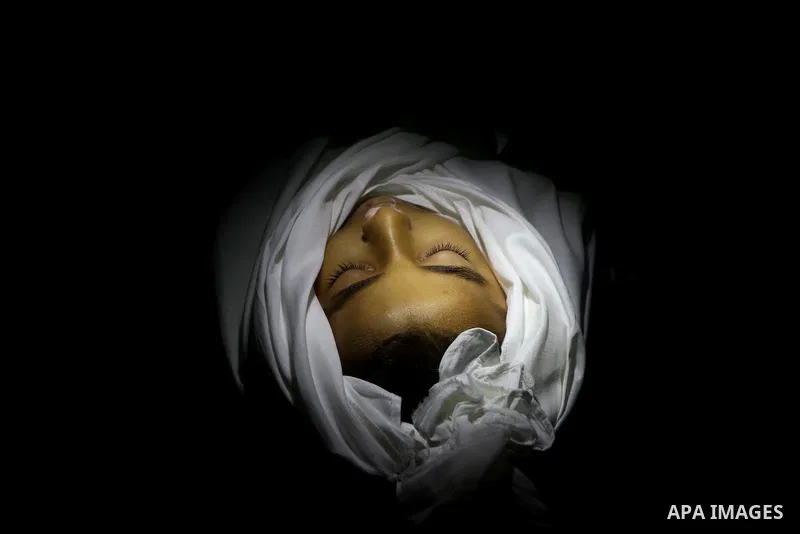 The body of Palestinian boy Ramadan al-Zaalan, 12, lies near mourners during his funeral in Gaza City on December 10, 2011. Zaalan was killed with his father Bahjat in an Israeli air strike on a civilian house in Gaza, m...