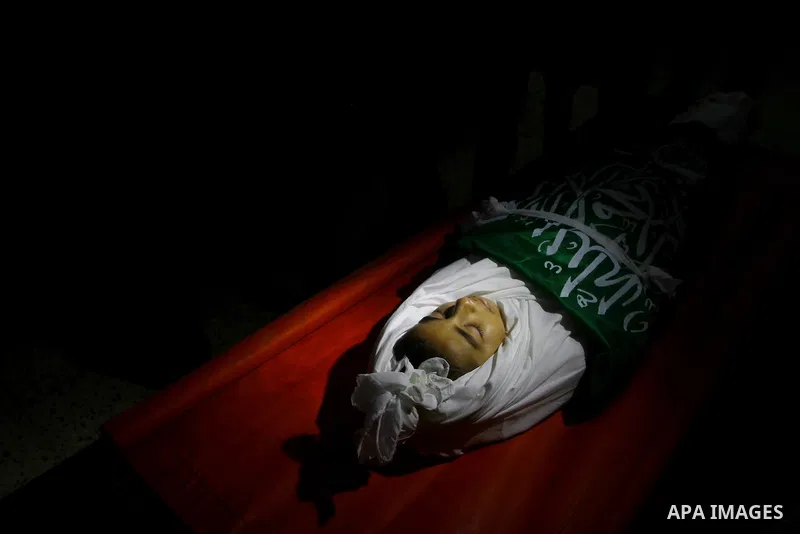 The body of Palestinian boy Ramadan al-Zaalan, 12, lies near mourners during his funeral in Gaza City on December 10, 2011. Zaalan was killed with his father Bahjat in an Israeli air strike on a civilian house in Gaza, m...