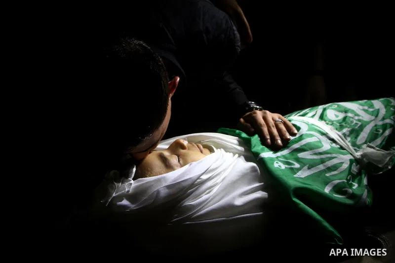 The body of Palestinian boy Ramadan al-Zaalan, 12, lies near mourners during his funeral in Gaza City on December 10, 2011. Zaalan was killed with his father Bahjat in an Israeli air strike on a civilian house in Gaza, m...
