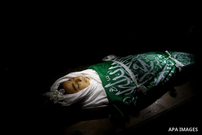 The body of Palestinian boy Ramadan al-Zaalan, 12, lies near mourners during his funeral in Gaza City on December 10, 2011. Zaalan was killed with his father Bahjat in an Israeli air strike on a civilian house in Gaza, m...