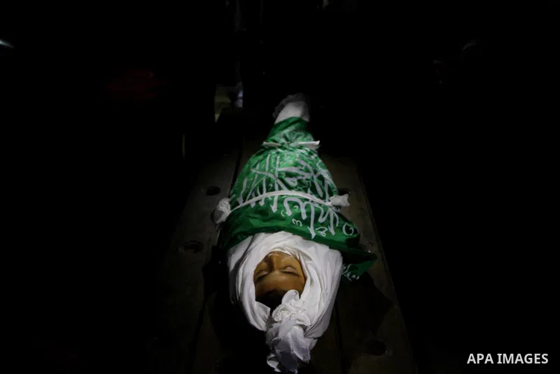 The body of Palestinian boy Ramadan al-Zaalan, 12, lies near mourners during his funeral in Gaza City on December 10, 2011. Zaalan was killed with his father Bahjat in an Israeli air strike on a civilian house in Gaza, m...