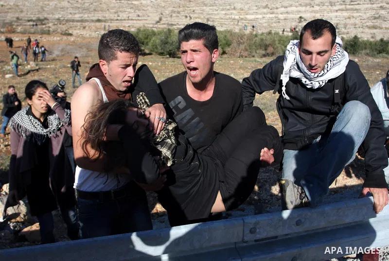 Palestinian demonstrators carry a protester away from tear gas fired by Israeli soldiers during clashes which erupted after the funeral of Palestinian Mustafa Tamimi in the West Bank town of Nabi Saleh, Sunday, Dec. 11,...