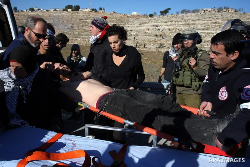 Palestinian demonstrators carry a protester away from tear gas fired by Israeli soldiers during clashes which erupted after the funeral of Palestinian Mustafa Tamimi in the West Bank town of Nabi Saleh, Sunday, Dec. 11,...