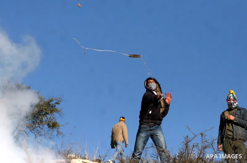Palestinian youths throw stones at Israeli soldiers during clashes which erupted after the funeral of Palestinian Mustafa Tamimi in the West Bank town of Nabi Saleh, Sunday, Dec. 11, 2011. Tamimi, 28, was hurling rocks a...