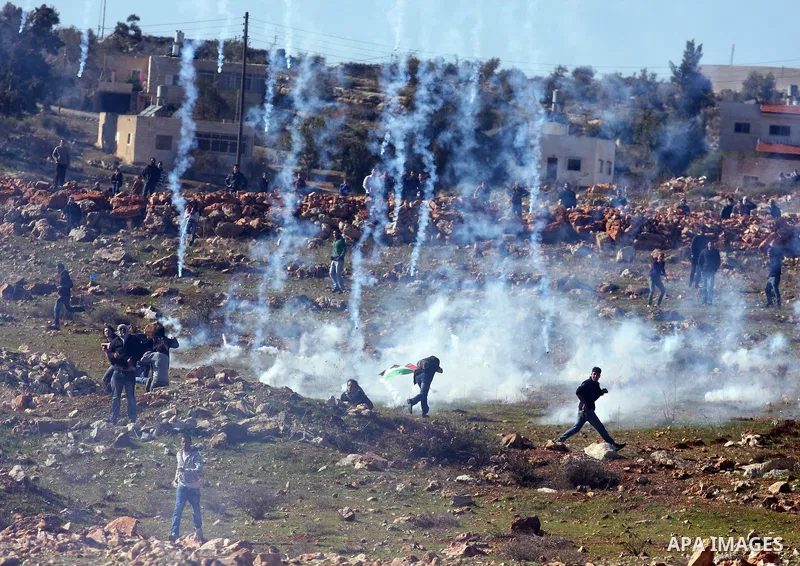 Palestinians try to avoid tear gas fired by Israeli soldiers during clashes which erupted after the funeral of Palestinian Mustafa Tamimi in the West Bank town of Nabi Saleh, Sunday, Dec. 11, 2011. Tamimi, 28, was hurlin...