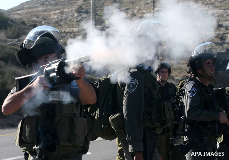 An Israeli soldier fires tear gas towards Palestinian demonstrators during clashes which erupted after the funeral of Palestinian Mustafa Tamimi in the West Bank town of Nabi Saleh, Sunday, Dec. 11, 2011. Tamimi, 28, was...
