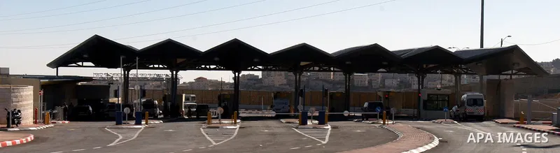Israeli soldiers stand guard as Palestinians cross through the new opened Israeli checkpoint near the east Jerusalem refugee camp of Shuafat on December 12, 2011. Palestinian youths protested against the construction of...