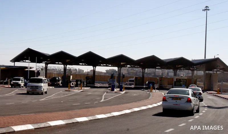 Israeli soldiers stand guard as Palestinians cross through the new opened Israeli checkpoint near the east Jerusalem refugee camp of Shuafat on December 12, 2011. Palestinian youths protested against the construction of...
