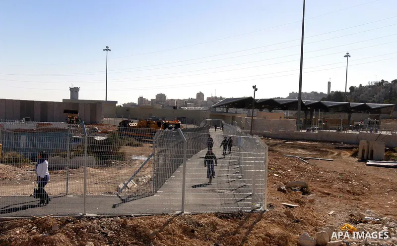 Israeli soldiers stand guard as Palestinians cross through the new opened Israeli checkpoint near the east Jerusalem refugee camp of Shuafat on December 12, 2011. Palestinian youths protested against the construction of...