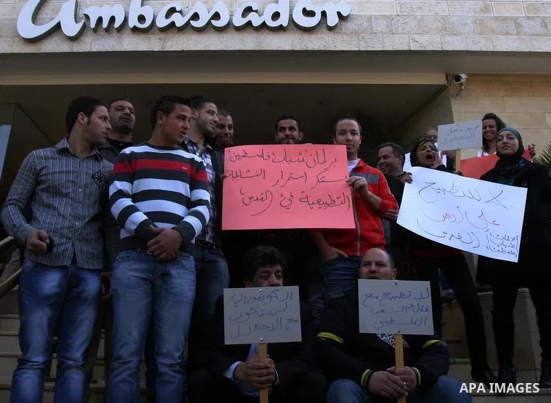 Palestinians hold placards during a protest against the normalization policy with Israel, in Jerusalem's neighbourhood of Sheikh Jarrah on Dec. 12,2011. Photo by Mahfouz Abu Turk