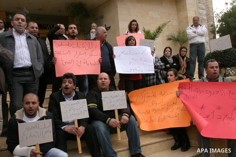 Palestinians hold placards during a protest against the normalization policy with Israel, in Jerusalem's neighbourhood of Sheikh Jarrah on Dec. 12,2011. Photo by Mahfouz Abu Turk