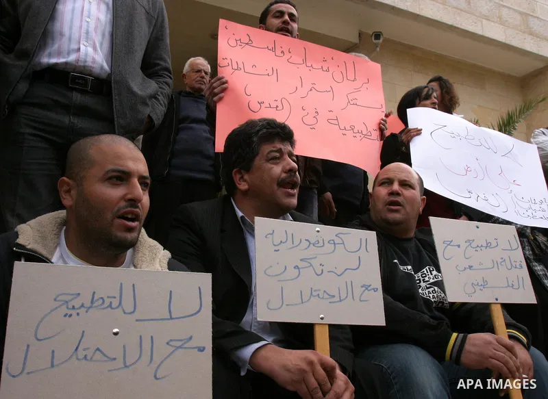 Palestinians hold placards during a protest against the normalization policy with Israel, in Jerusalem's neighbourhood of Sheikh Jarrah on Dec. 12,2011. Photo by Mahfouz Abu Turk