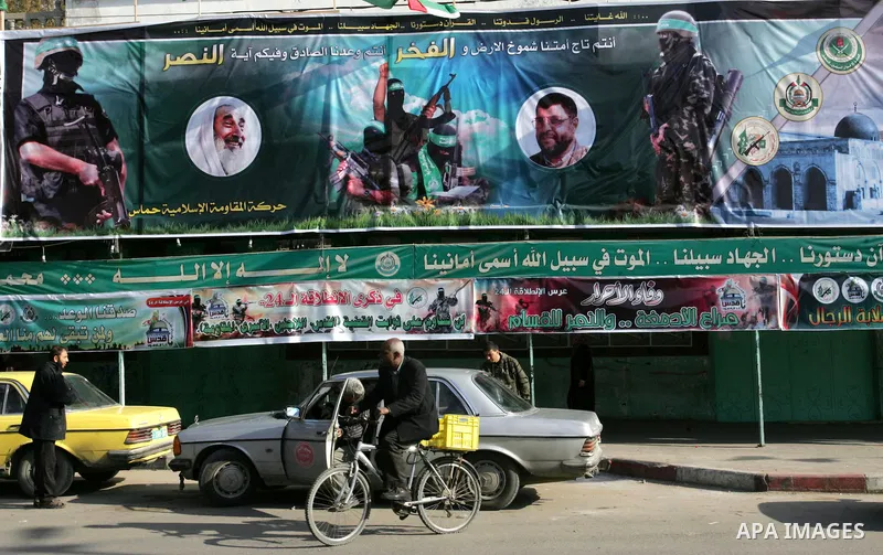 Palestinians walk past murals depicting slogans for Hamas in preparation for the celebrations marking the Islamist movement's 24th anniversary, Rafah refugee camp, in southern Gaza Strip on Dec. 13,2011. The main celebra...