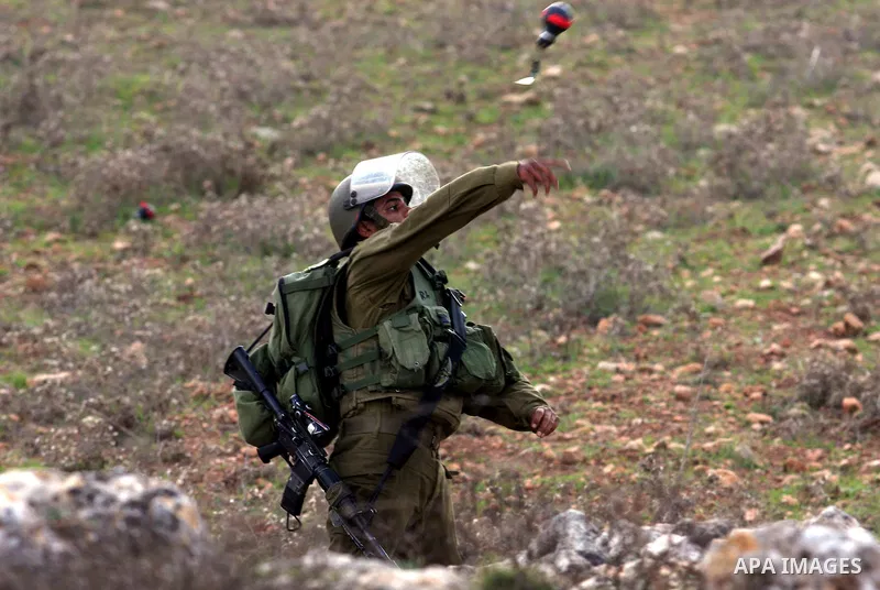 An Israeli soldier hurls tear gas canister towards Palestinian demonstrators during clashes at a weekly protest against a nearby Jewish settlement, in the West Bank village of Nabi Saleh, near Ramallah December 16, 2011....