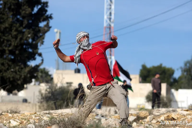 A Palestinian demonstrator hurls a stone towards Israeli security forces during clashes at a weekly protest against a nearby Jewish settlement, in the West Bank village of Nabi Saleh, near Ramallah December 16, 2011. Som...