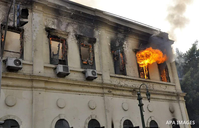 Egyptian demonstrators throw stones towards security forces in front of a building in fire, in Kasr al-Aini Cairo, Egypt, 17 December 2011. Accoring to media reports, The clashes, the worst in three weeks, erupted on 16...