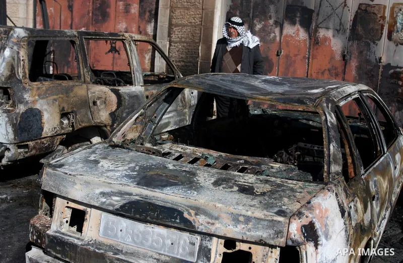 A Palestinian man inspects burnt cars after unidentified assailants torched them in the West Bank village of Beitin, north of Ramallah, on December 19, 2011 in a possible revenge attack by extremist Jews, police said. Ph...