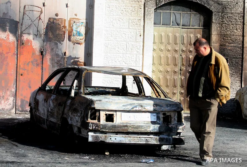 A Palestinian man inspects burnt cars after unidentified assailants torched them in the West Bank village of Beitin, north of Ramallah, on December 19, 2011 in a possible revenge attack by extremist Jews, police said. Ph...