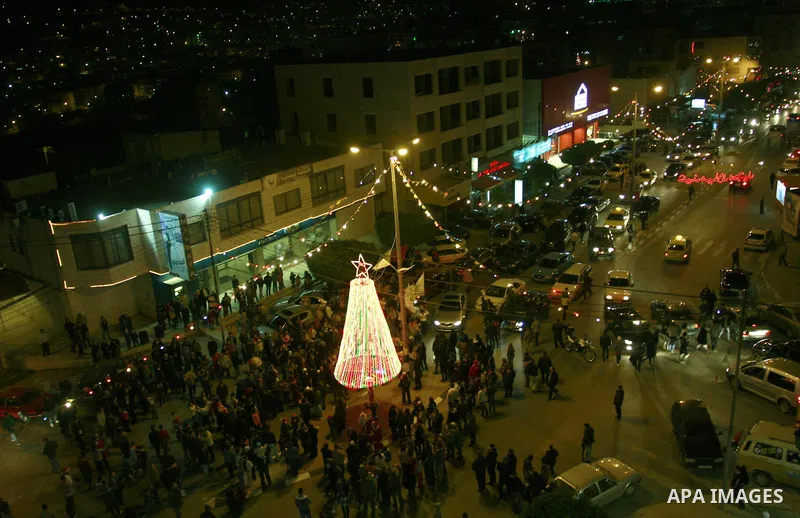 Palestinians watch the lighting of a Christmas tree outside the Church in West Bank town of Nablus Monday, Dec. 19, 2011. Christian worshipers began their spiritual preparations ahead of Christmas Eve and tourists from a...