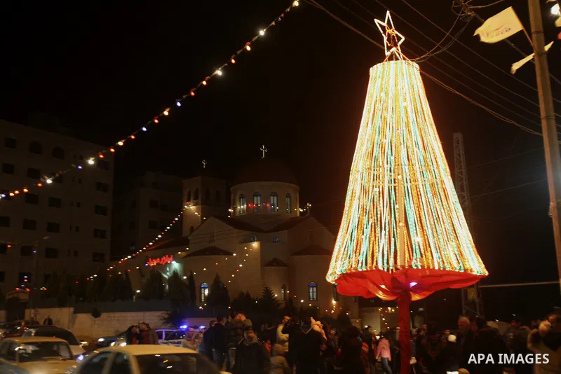 Palestinians watch the lighting of a Christmas tree outside the Church in West Bank town of Nablus Monday, Dec. 19, 2011. Christian worshipers began their spiritual preparations ahead of Christmas Eve and tourists from a...