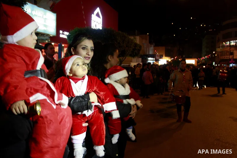 Palestinians watch the lighting of a Christmas tree outside the Church in West Bank town of Nablus Monday, Dec. 19, 2011. Christian worshipers began their spiritual preparations ahead of Christmas Eve and tourists from a...