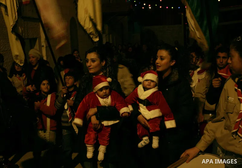 Palestinians watch the lighting of a Christmas tree outside the Church in West Bank town of Nablus Monday, Dec. 19, 2011. Christian worshipers began their spiritual preparations ahead of Christmas Eve and tourists from a...