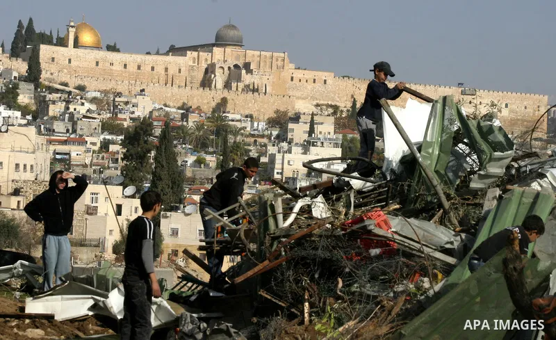 Palestinians sit on the rubble of a storehouse after an Israeli bulldozer destroys a storehouse in east Jerusalem neighborhood of Silwan on Dec 20,2011, where Palestinian houses are threatened to be demolished by the Isr...