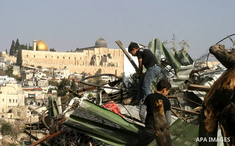 Palestinians sit on the rubble of a storehouse after an Israeli bulldozer destroys a storehouse in east Jerusalem neighborhood of Silwan on Dec 20,2011, where Palestinian houses are threatened to be demolished by the Isr...