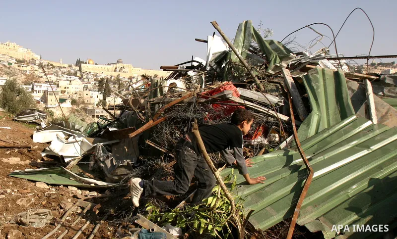 Palestinians sit on the rubble of a storehouse after an Israeli bulldozer destroys a storehouse in east Jerusalem neighborhood of Silwan on Dec 20,2011, where Palestinian houses are threatened to be demolished by the Isr...