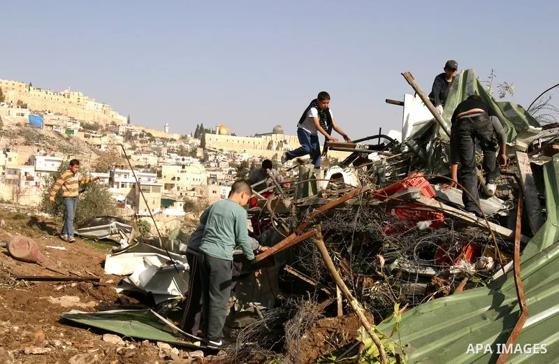 Palestinians sit on the rubble of a storehouse after an Israeli bulldozer destroys a storehouse in east Jerusalem neighborhood of Silwan on Dec 20,2011, where Palestinian houses are threatened to be demolished by the Isr...