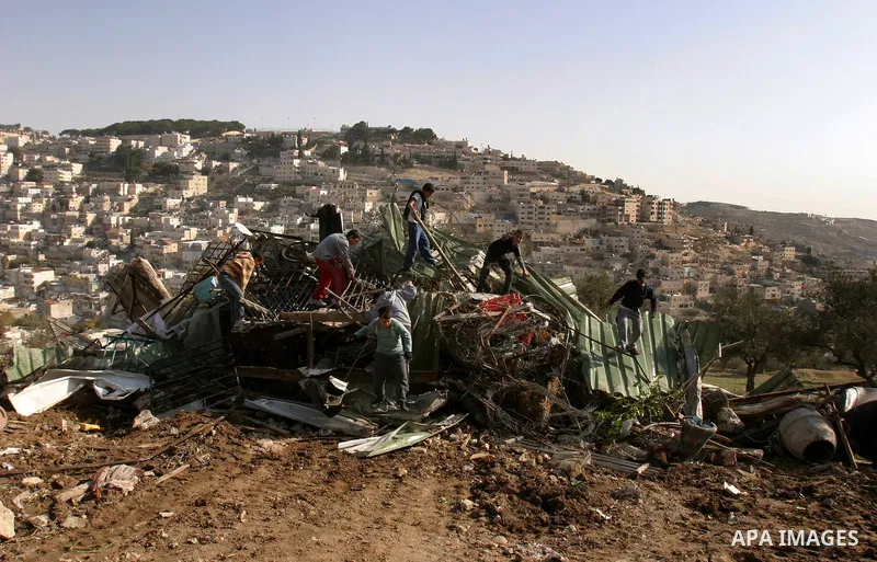 Palestinians sit on the rubble of a storehouse after an Israeli bulldozer destroys a storehouse in east Jerusalem neighborhood of Silwan on Dec 20,2011, where Palestinian houses are threatened to be demolished by the Isr...